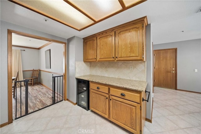 kitchen featuring wine cooler, brown cabinets, backsplash, and baseboards