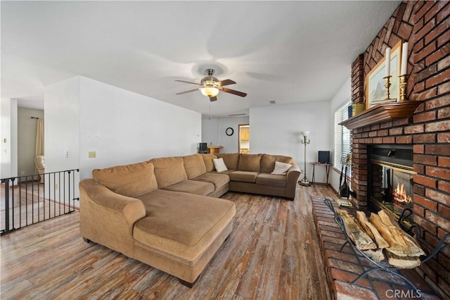 living area with a ceiling fan, a fireplace, and wood finished floors