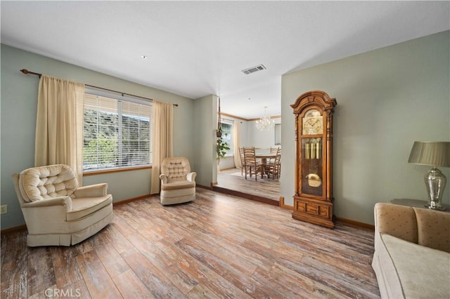 living area featuring an inviting chandelier, wood finished floors, visible vents, and a healthy amount of sunlight