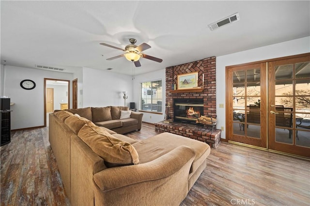 living area with a fireplace, wood finished floors, visible vents, and a ceiling fan