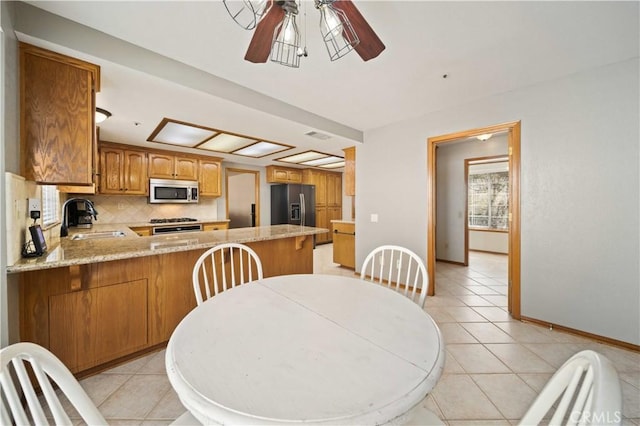 kitchen featuring stainless steel microwave, a sink, refrigerator with ice dispenser, and light tile patterned flooring