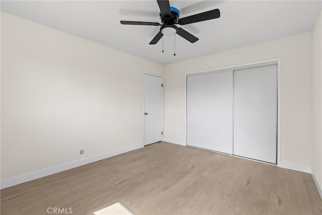 unfurnished bedroom with a closet, wood finished floors, a ceiling fan, and baseboards