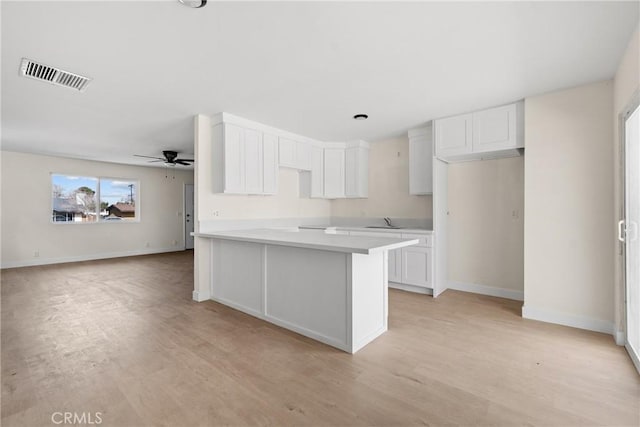 kitchen featuring light countertops, light wood-type flooring, visible vents, and white cabinets