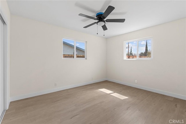 spare room featuring ceiling fan, light wood finished floors, and baseboards