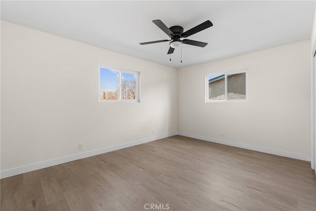 spare room featuring ceiling fan, baseboards, and wood finished floors