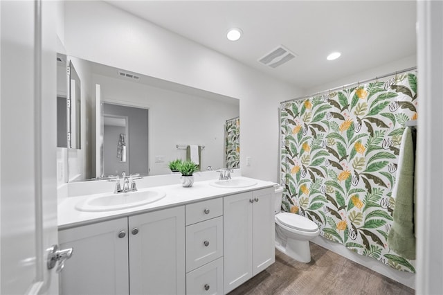 bathroom featuring double vanity, visible vents, toilet, and a sink