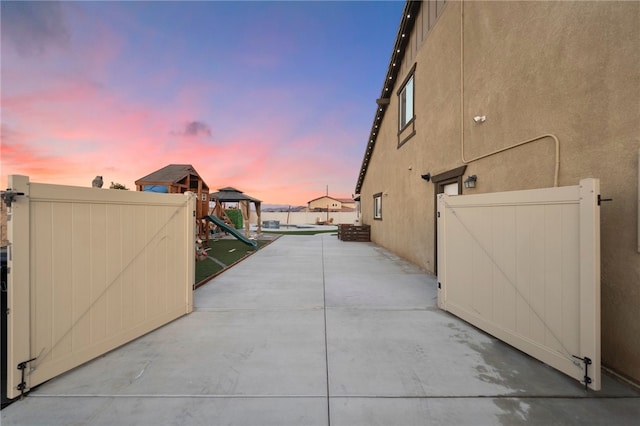 exterior space with stucco siding, fence, a patio, and a gate