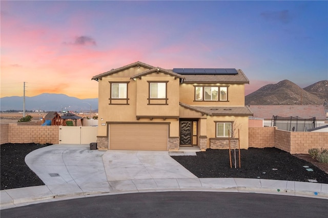 view of front of house with solar panels, fence, concrete driveway, stucco siding, and a gate