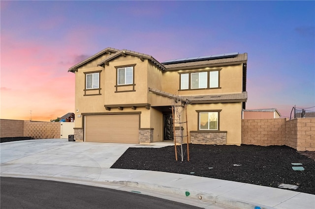 traditional-style house featuring fence, an attached garage, stucco siding, concrete driveway, and roof mounted solar panels