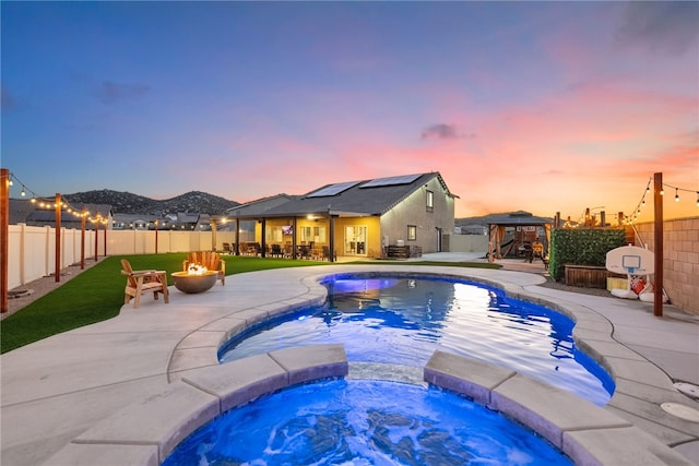 view of pool featuring a pool with connected hot tub, a fire pit, a gazebo, a fenced backyard, and a patio area