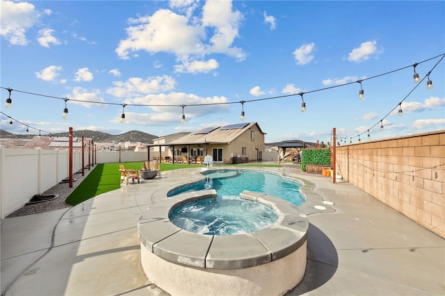 view of swimming pool featuring a patio, a fenced backyard, and a pool with connected hot tub