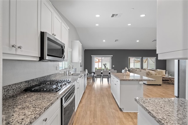 kitchen featuring visible vents, a sink, a kitchen island, appliances with stainless steel finishes, and light wood finished floors