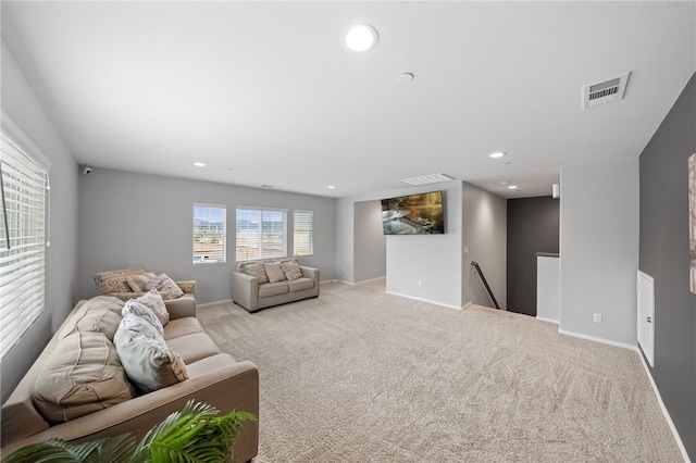 living room with recessed lighting, visible vents, light colored carpet, and baseboards