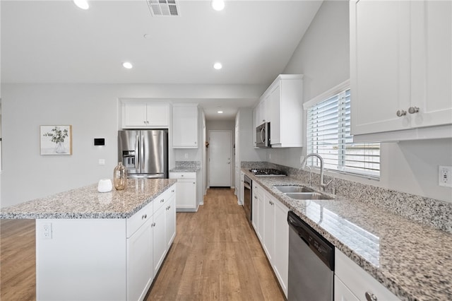 kitchen with visible vents, a center island, light wood-type flooring, stainless steel appliances, and a sink