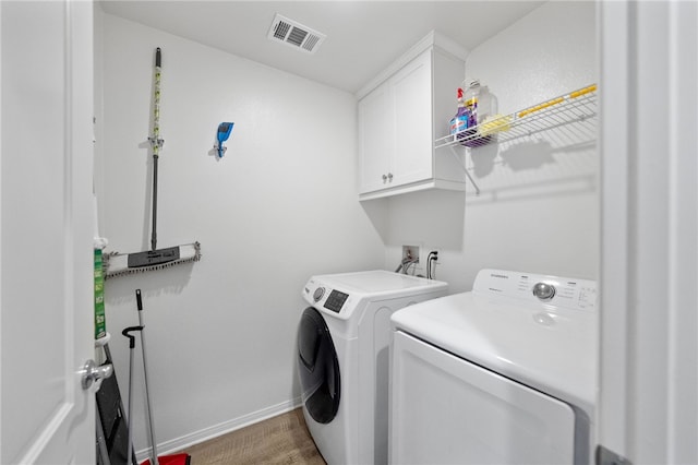 laundry area featuring visible vents, wood finished floors, cabinet space, baseboards, and washing machine and clothes dryer