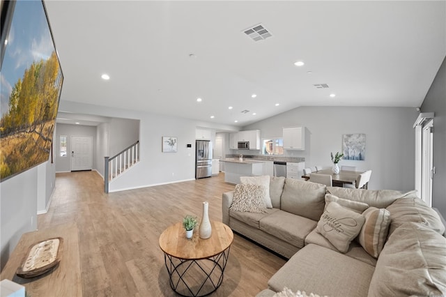 living area featuring visible vents, recessed lighting, stairs, vaulted ceiling, and light wood-style floors