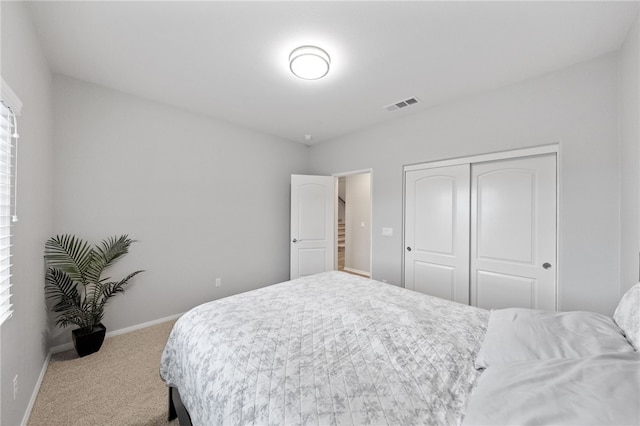 carpeted bedroom featuring visible vents, baseboards, and a closet