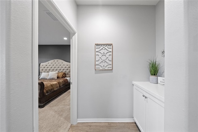 corridor with baseboards and light colored carpet