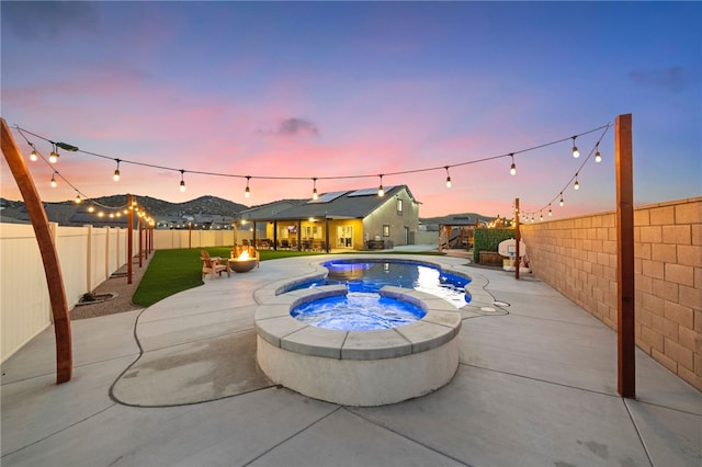 view of swimming pool with a patio area, a fenced backyard, a pool with connected hot tub, and a fire pit