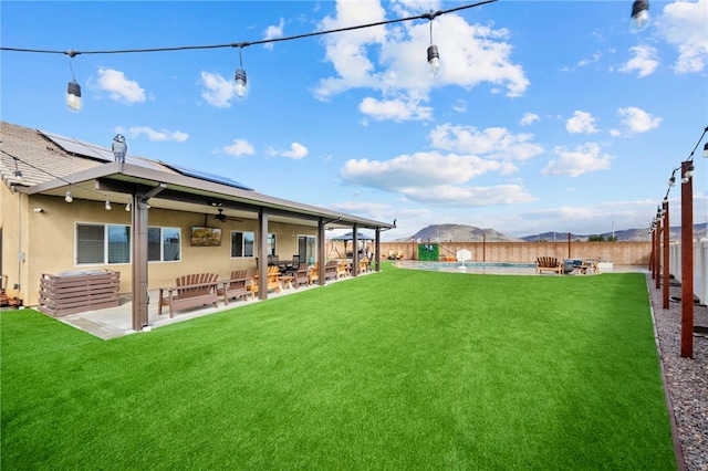 view of yard featuring a fenced backyard, a mountain view, a fenced in pool, ceiling fan, and a patio area