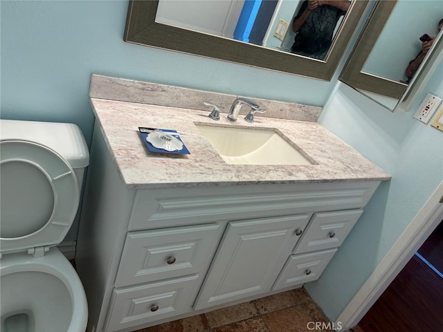 half bath featuring stacked washer / drying machine, vanity, and toilet