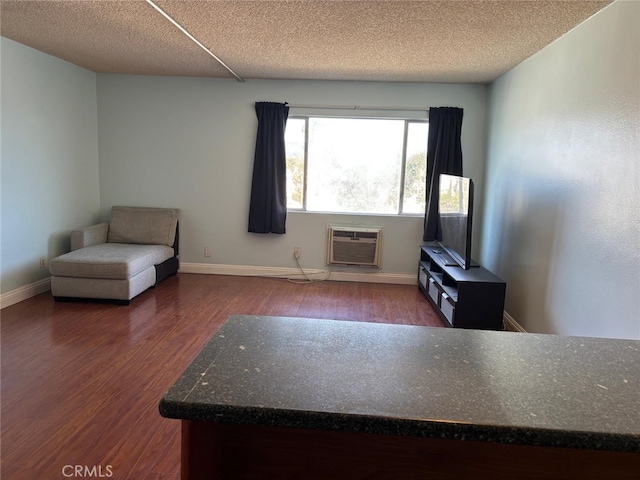 unfurnished room with a textured ceiling, baseboards, wood finished floors, and a wall mounted air conditioner