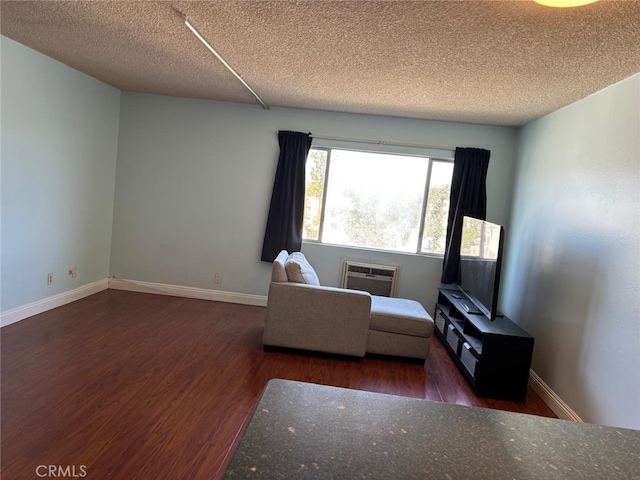 living area featuring a textured ceiling, baseboards, and wood finished floors