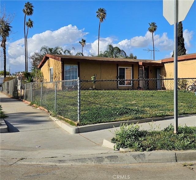 view of front facade with a fenced front yard, a front lawn, and stucco siding