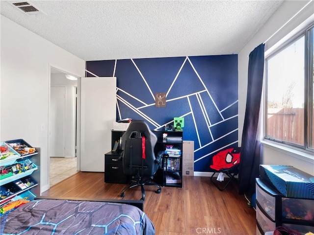 bedroom with a textured ceiling, wood finished floors, and visible vents