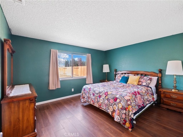 bedroom featuring a textured ceiling, baseboards, and wood finished floors