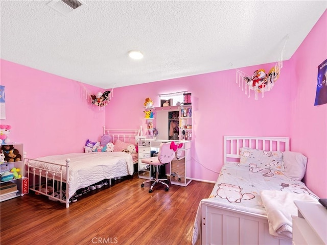 bedroom featuring a textured ceiling, wood finished floors, and visible vents