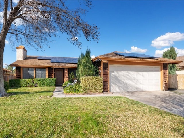 view of front facade featuring driveway, roof mounted solar panels, fence, and a front lawn