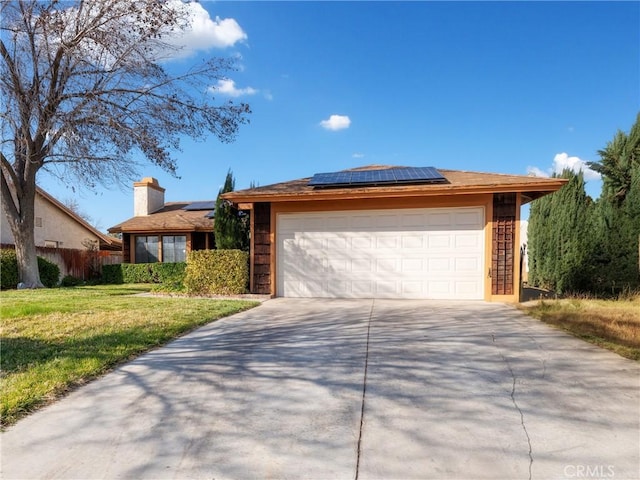 view of front of home with a garage, solar panels, concrete driveway, fence, and a front lawn