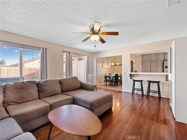 living room featuring ceiling fan, a textured ceiling, and wood finished floors