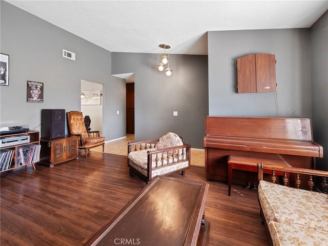 living room with lofted ceiling, visible vents, and wood finished floors