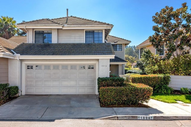 traditional home featuring driveway, a tile roof, an attached garage, and stucco siding