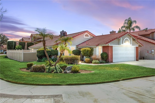 view of front facade featuring a front yard, fence, concrete driveway, and a tiled roof