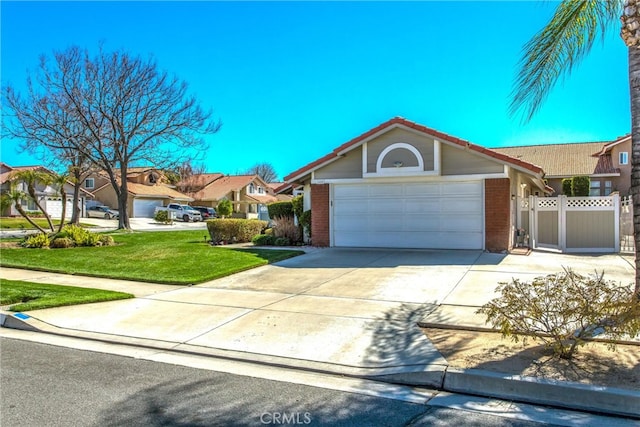 view of front facade with concrete driveway, brick siding, fence, and a front lawn