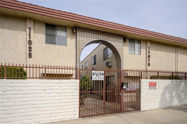 view of front facade featuring a fenced front yard, a gate, and stucco siding