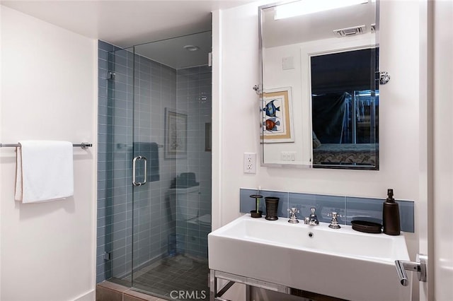 full bath with visible vents, a sink, a shower stall, and decorative backsplash