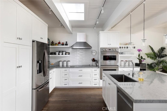 kitchen featuring wall chimney range hood, appliances with stainless steel finishes, open shelves, and a sink