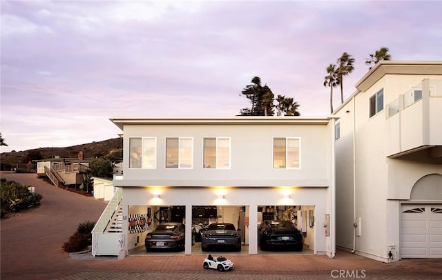 view of front facade featuring a garage, decorative driveway, and stucco siding