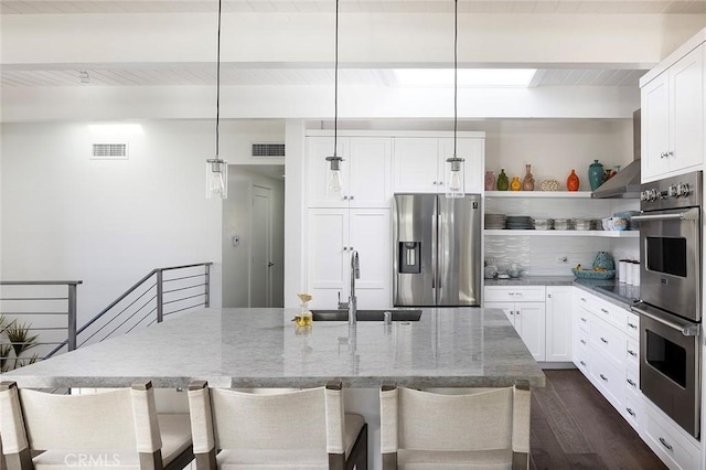 kitchen featuring light stone counters, stainless steel appliances, a sink, visible vents, and beam ceiling