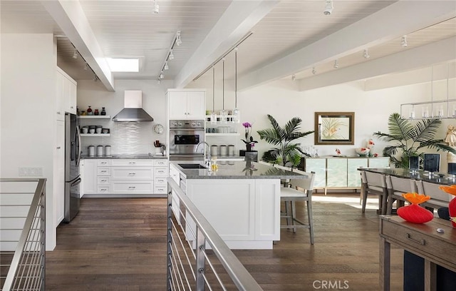 kitchen with wall chimney range hood, a kitchen bar, open shelves, and dark wood-style flooring