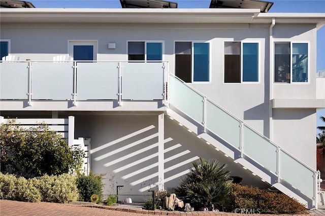 view of side of home with a balcony and stucco siding