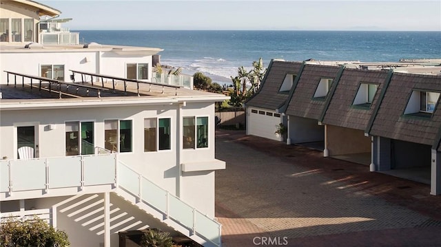 view of property exterior featuring a garage, a water view, a view of the beach, and stucco siding