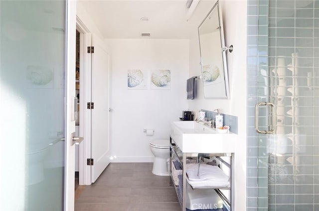 bathroom with visible vents, toilet, a shower stall, vanity, and baseboards