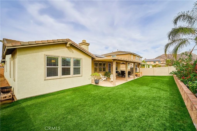 rear view of house with a fenced backyard, a ceiling fan, a lawn, stucco siding, and a patio area