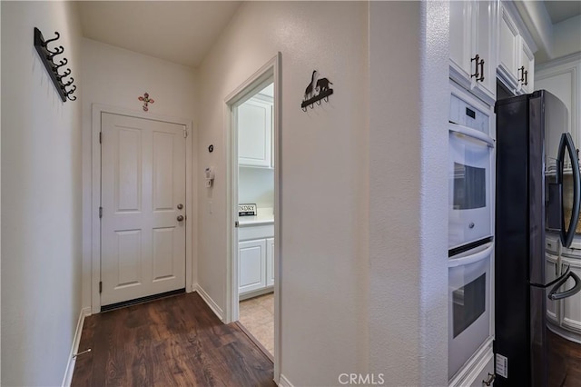 corridor featuring dark wood-style flooring and baseboards