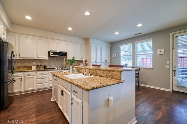 kitchen with visible vents, white cabinets, dark wood finished floors, stainless steel appliances, and a sink